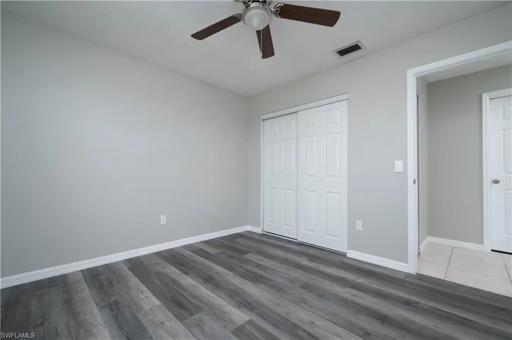 Unfurnished bedroom featuring ceiling fan, dark wood-type flooring, visible vents, baseboards, and a closet