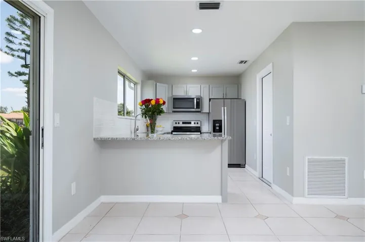 Kitchen with visible vents, stainless steel appliances, light stone counters, and gray cabinetry