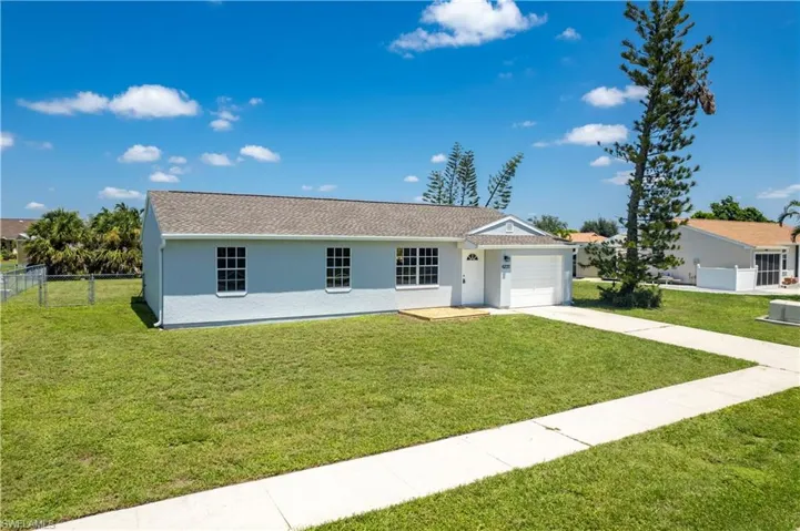 Ranch-style home featuring a garage, concrete driveway, fence, a front yard, and stucco siding