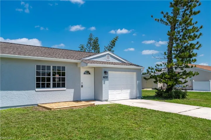 Ranch-style home featuring an attached garage, driveway, a front lawn, and stucco siding