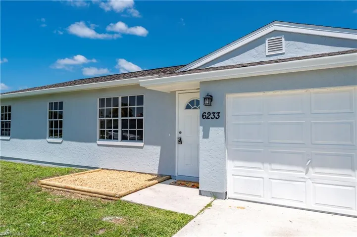 View of front facade with a garage and stucco siding