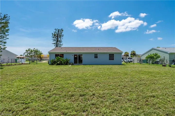 Back of property with a lawn, fence, and stucco siding