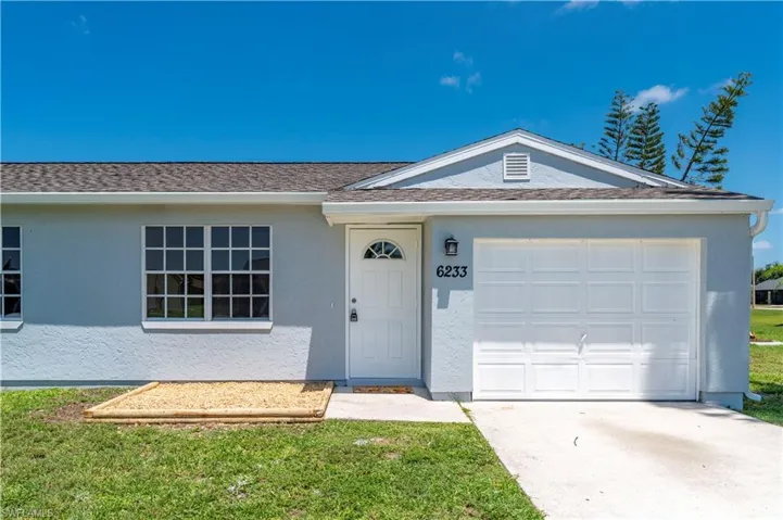 Single story home with a garage, driveway, a front yard, and stucco siding