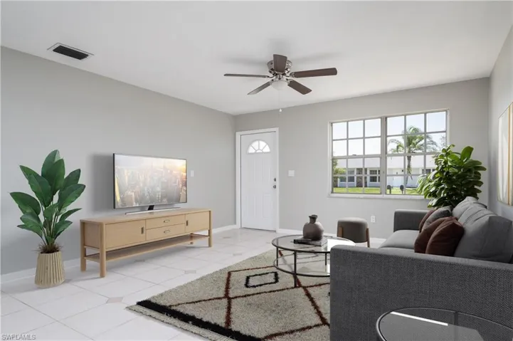 Living room with light tile patterned floors, Virtually Staged baseboards, visible vents, and a ceiling fan