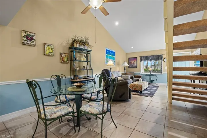 Tiled dining area with ceiling fan and high vaulted ceiling
