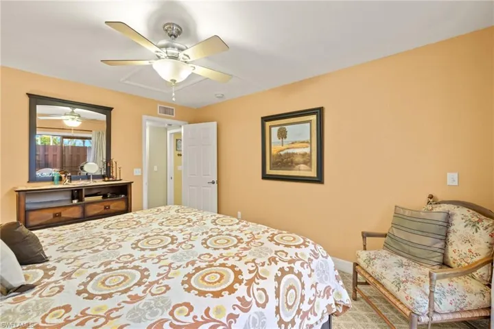 Downstairs bedroom offers a ceiling fan and carpet.