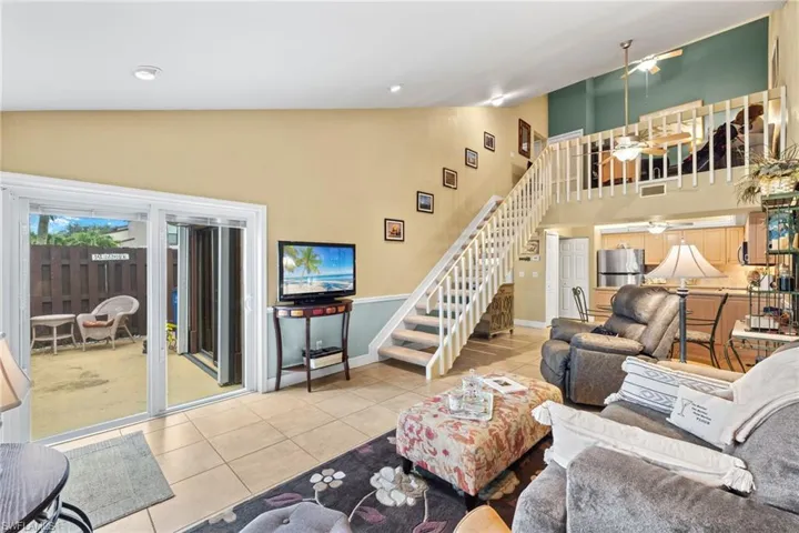 Living room with light tile patterned floors, ceiling fan, and vaulted ceiling.