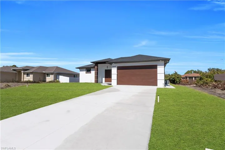 Prairie-style home with a front yard, concrete driveway, stucco siding, and an attached garage