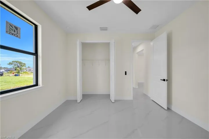 Unfurnished bedroom featuring light marble finish flooring, a closet, and a ceiling fan