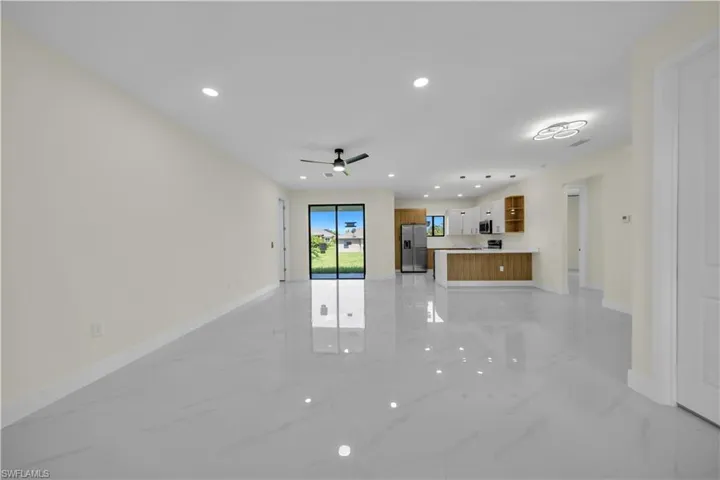 Unfurnished living room with light marble finish flooring, recessed lighting, and ceiling fan