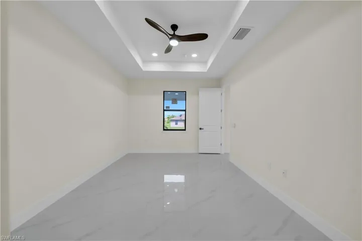 Empty room featuring marble tiled floors, recessed lighting, a raised ceiling, and ceiling fan