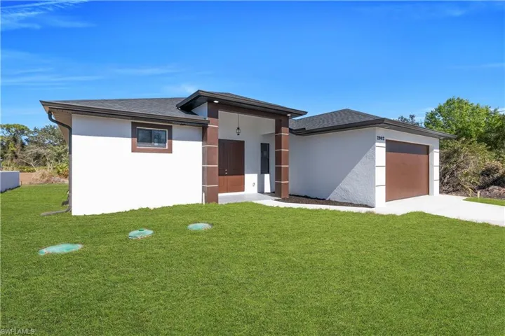 Prairie-style home with a front lawn, stucco siding, a garage, and concrete driveway