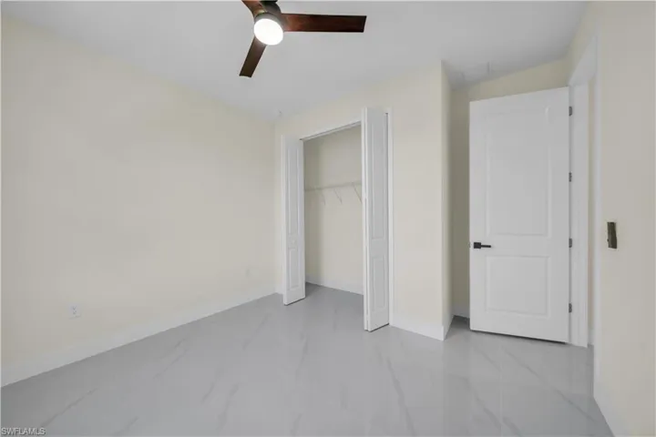 Unfurnished bedroom featuring a ceiling fan, a closet, and light marble finish flooring