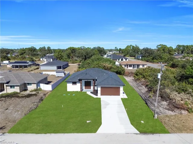 View of front of home featuring concrete driveway, a residential view, a garage, and view of wooded area