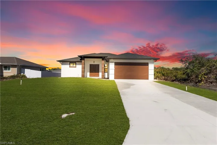 Prairie-style home featuring driveway, stucco siding, and an attached garage