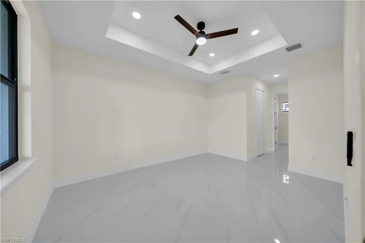 Spare room featuring recessed lighting, a raised ceiling, ceiling fan, and marble finish flooring