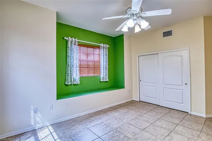 Unfurnished bedroom with a ceiling fan, light tile patterned floors, and a closet