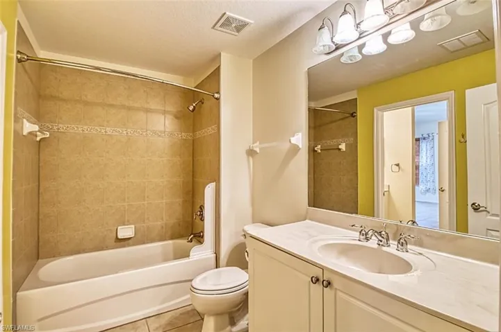 Bathroom with vanity, light tile patterned floors, tub / shower combination, and a textured ceiling