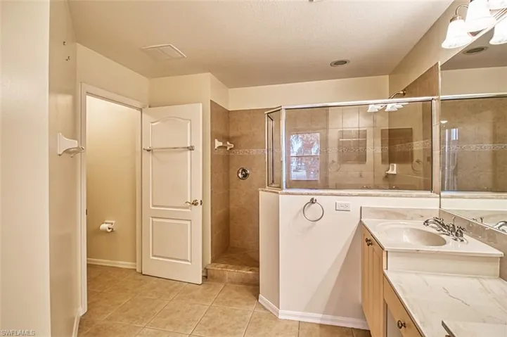 Full bath with vanity, walk in shower, light tile patterned floors, and a textured ceiling