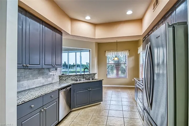 Kitchen featuring stainless steel appliances, light stone counters, backsplash, and light tile patterned floors
