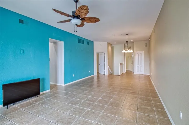 Unfurnished living room featuring ceiling fan, suspended lighting, and light tile patterned floors