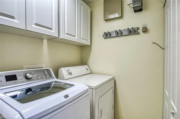 Laundry room featuring a textured wall, cabinet space, and separate washer and dryer