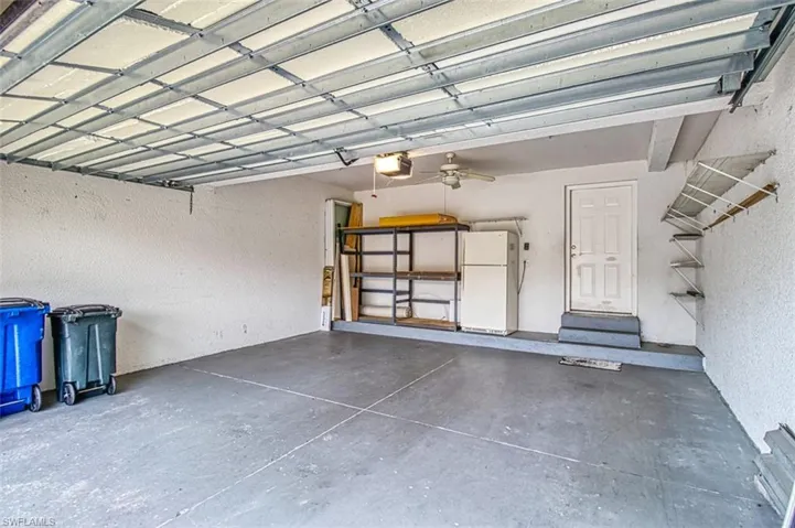 Garage featuring freestanding refrigerator, a textured wall, and a garage door opener