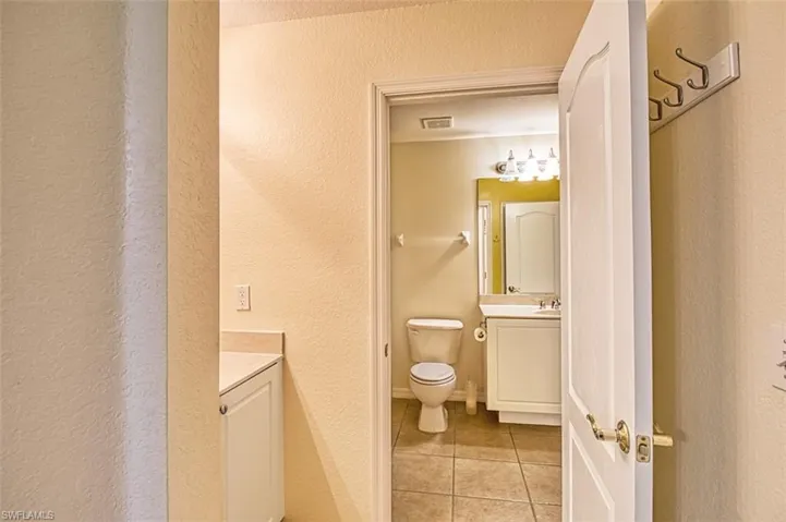 Bathroom with a textured wall, vanity, and light tile patterned flooring