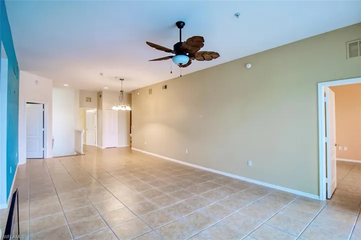 Spare room featuring ceiling fan, hanging lights, and light tile patterned floors