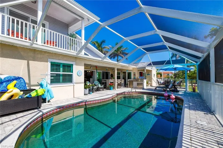 Swimming pool with a patio, glass enclosure, an outdoor kitchen, and ceiling fan