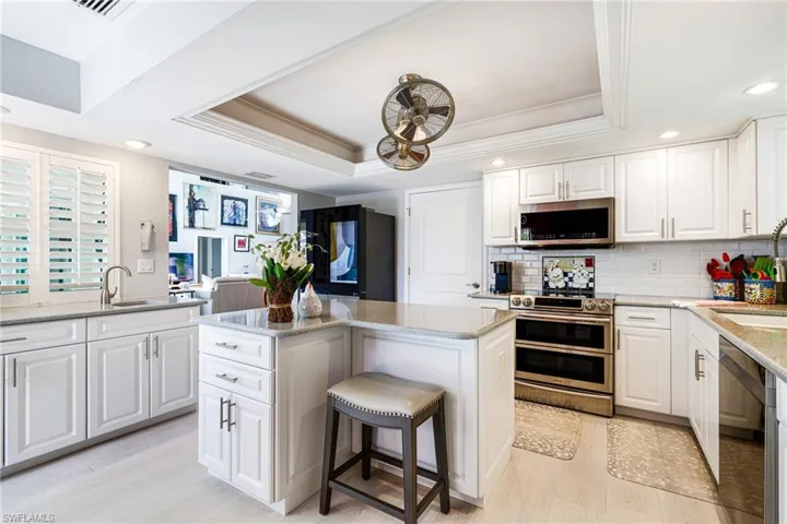 Kitchen with recessed lighting, a tray ceiling, crown molding, backsplash, and appliances with stainless steel finishes