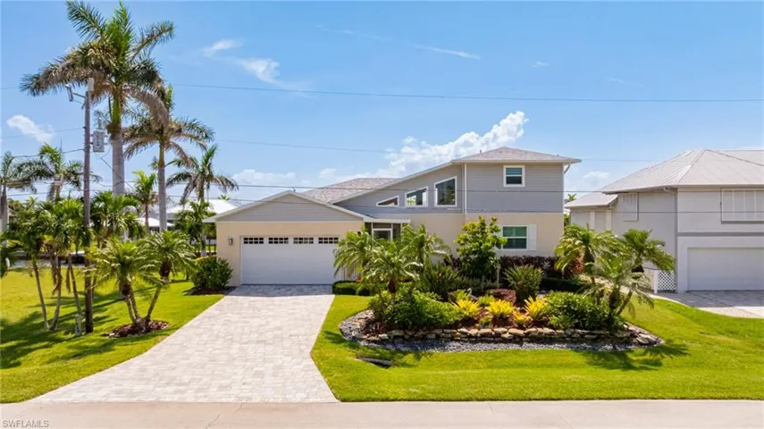 View of front facade featuring decorative driveway, a garage, and a front lawn