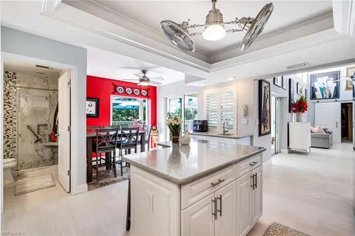 Kitchen featuring a tray ceiling, a kitchen island, light wood-type flooring, white cabinetry, and crown molding