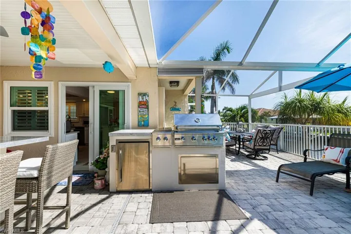 View of patio with glass enclosure and exterior kitchen