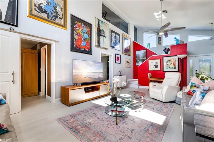 Living area featuring a towering ceiling, wood finished floors, and a ceiling fan