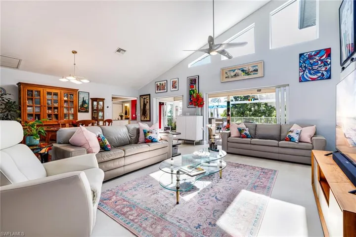 Living room featuring a ceiling fan, high vaulted ceiling, and a chandelier