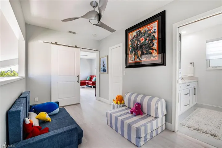 Sitting room featuring a barn door, light wood finished floors, and a ceiling fan