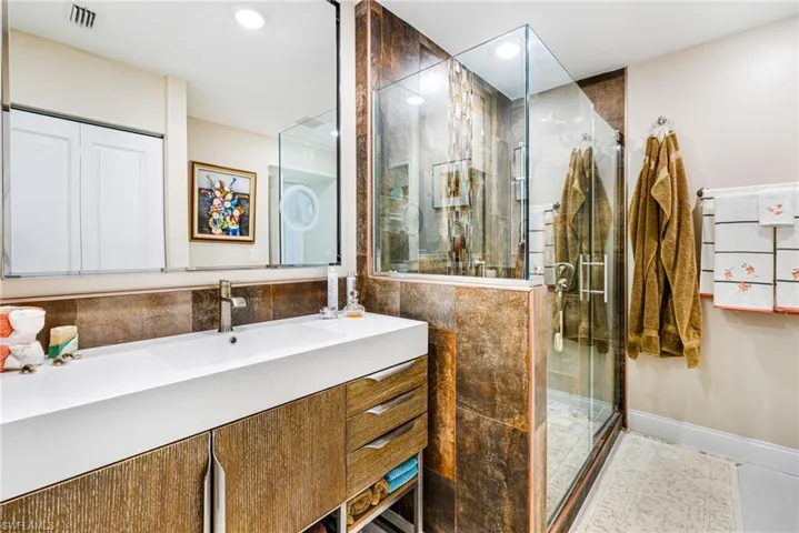 Bathroom with a stall shower, vanity, and recessed lighting