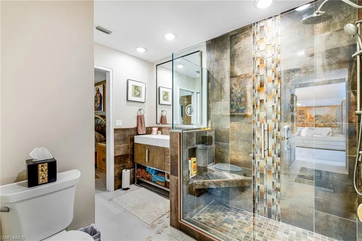 Bathroom with vanity, a stall shower, recessed lighting, and tile walls