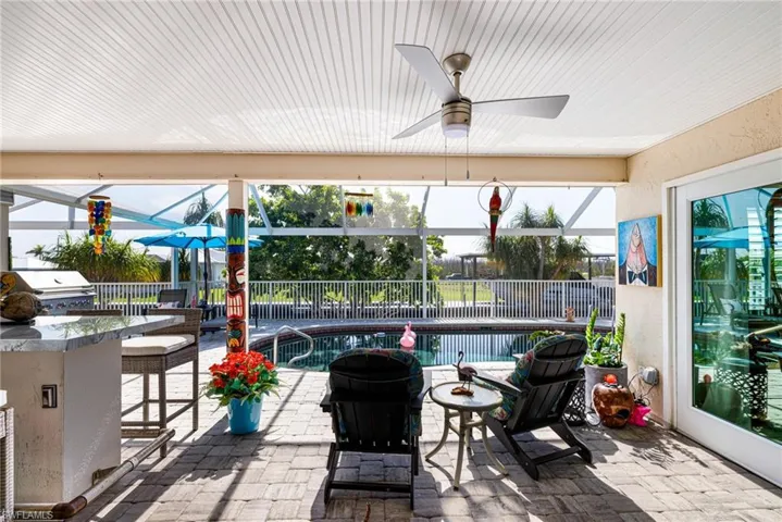 View of patio with glass enclosure, area for grilling, and ceiling fan