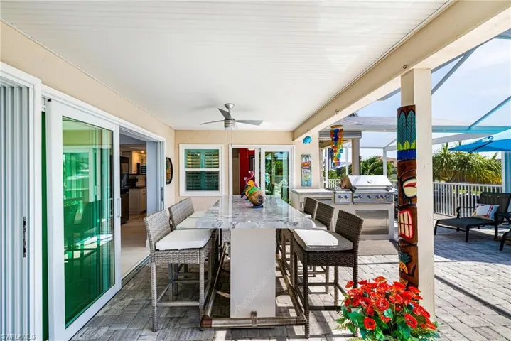 View of patio with ceiling fan, area for grilling, and glass enclosure