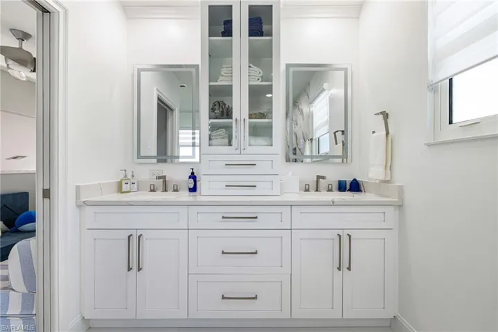Ensuite bathroom featuring double vanity and baseboards
