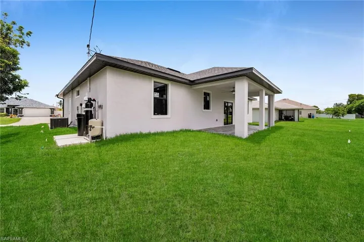 Rear view of house featuring central AC unit, a yard, and a patio area