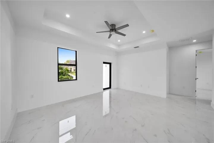 Spare room featuring ceiling fan, a tray ceiling, and light tile patterned floors