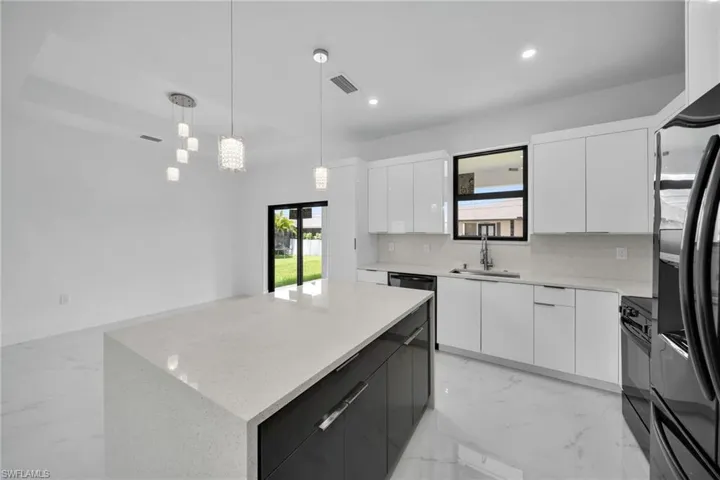 Kitchen with white cabinets, sink, hanging light fixtures, a kitchen island, and decorative backsplash