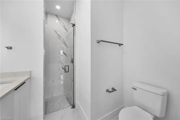Bathroom with vanity, toilet, a tile shower, and tile patterned floors