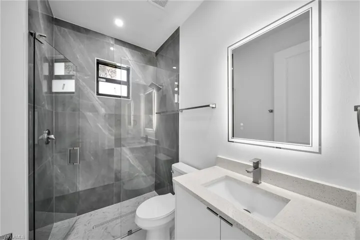 Bathroom with vanity, a shower with door, and toilet