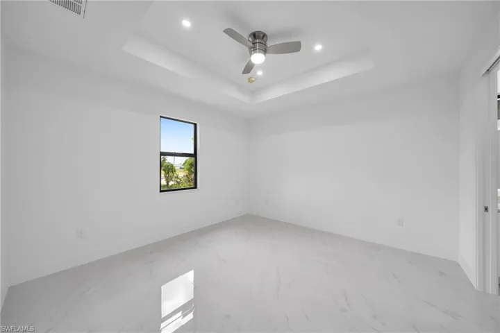 Tiled spare room with ceiling fan and a raised ceiling
