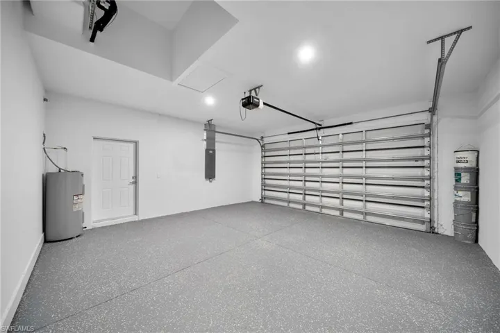 Garage with electric panel, a garage door opener, and water heater