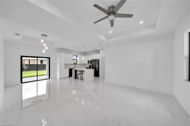 Unfurnished living room featuring light tile patterned floors, a raised ceiling, and ceiling fan